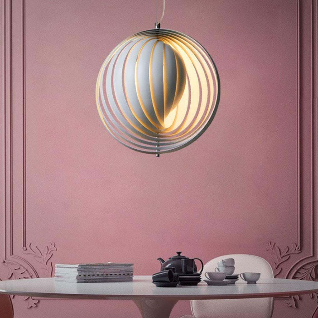Clérachic Round Metal Pendant Light over a white dining table, slatted globe glowing against a dusty-pink wall.
