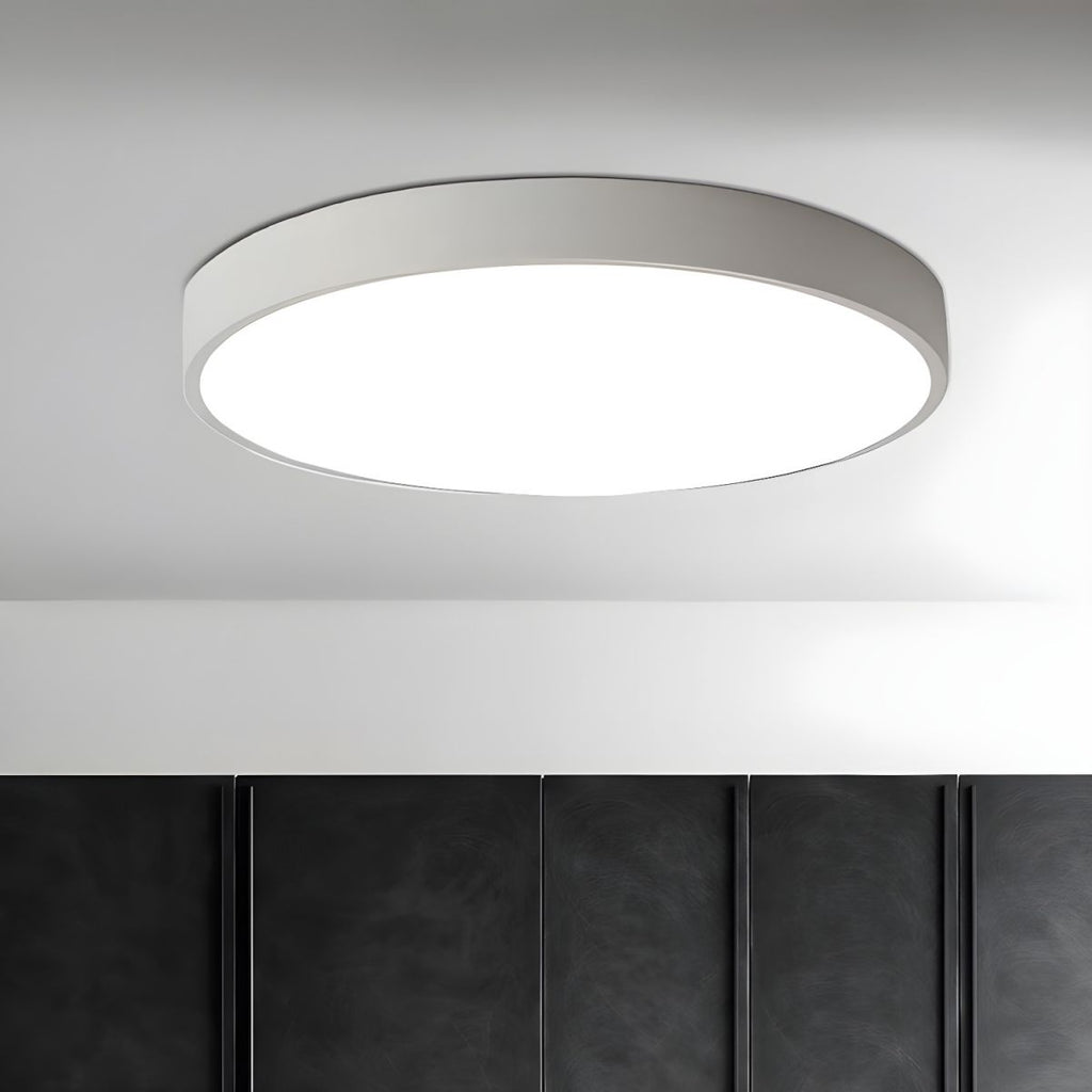 A white-framed round Clérachic ceiling light lit above a wall of dark panelled cupboard doors.