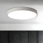 A white-framed round Clérachic ceiling light lit above a wall of dark panelled cupboard doors.