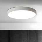 White round Clérachic ceiling light, lit, on a pale ceiling above a dark quilted wall panel.