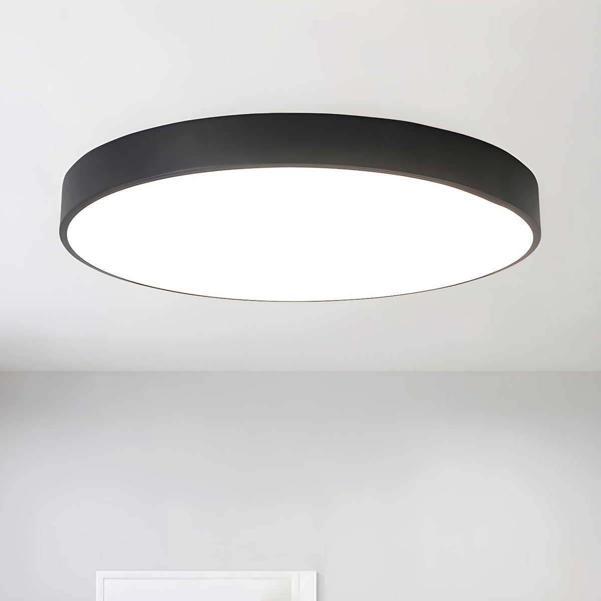 Large black round Clérachic ceiling light glowing white from below, on a light grey ceiling.