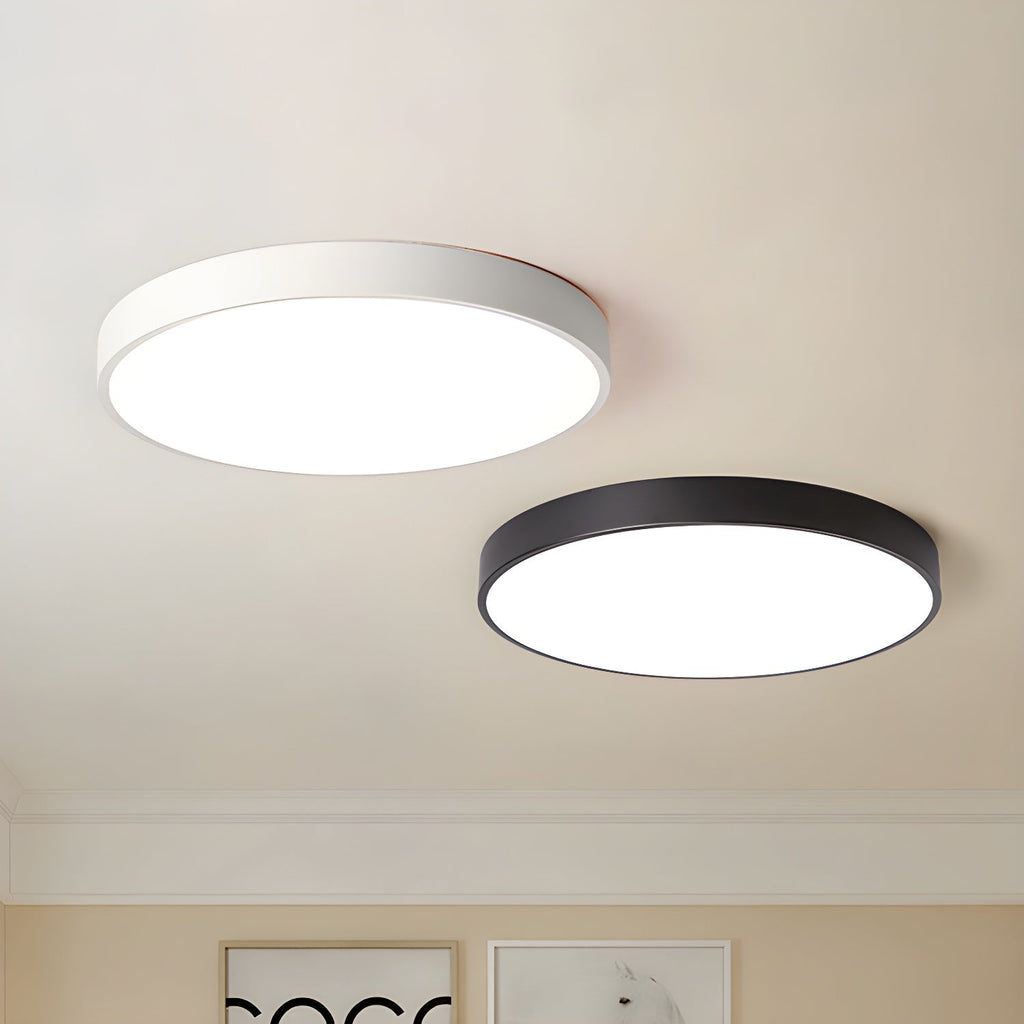 Two Clérachic round ceiling lights, one white-framed and one black, lit on a cream ceiling above framed prints.