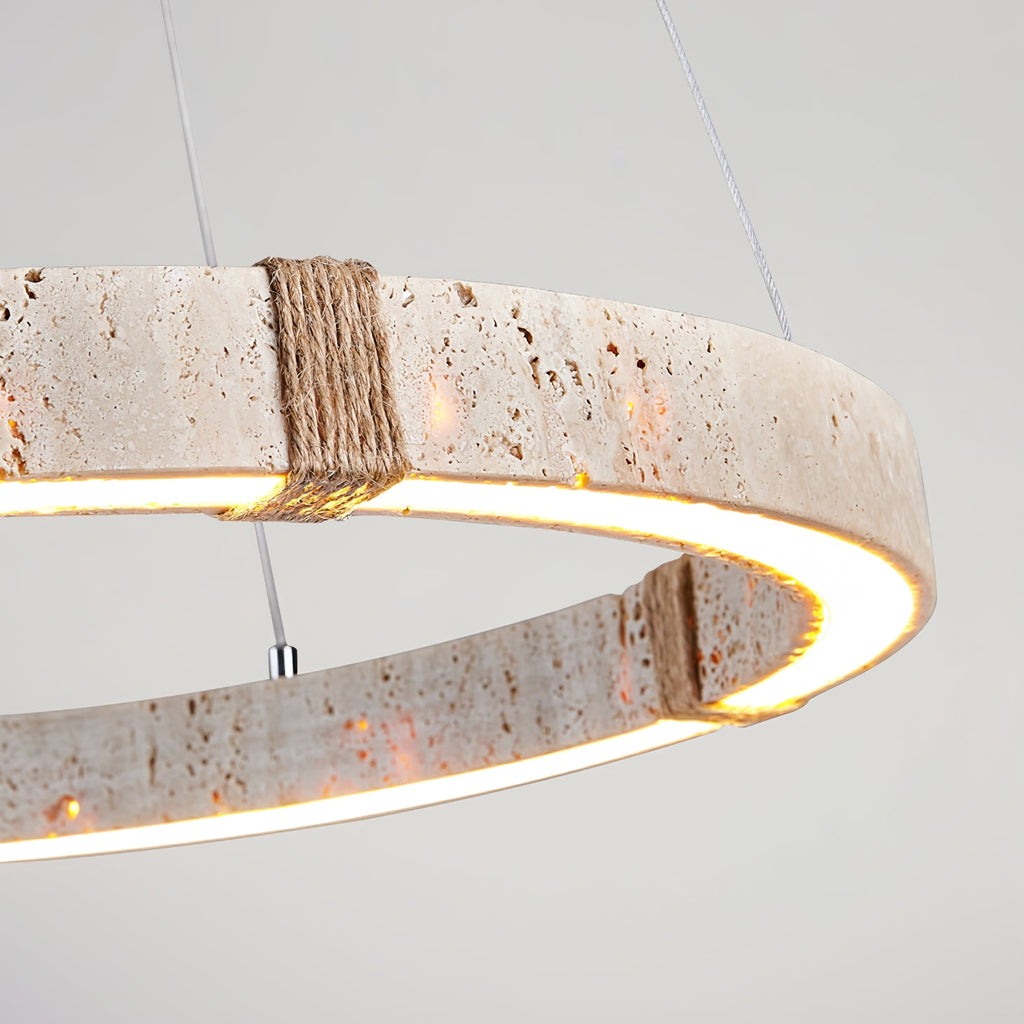 Close detail of the pitted travertine and the rope-wrapped joint on this Clérachic ring pendant, with a warm LED glow under the stone.