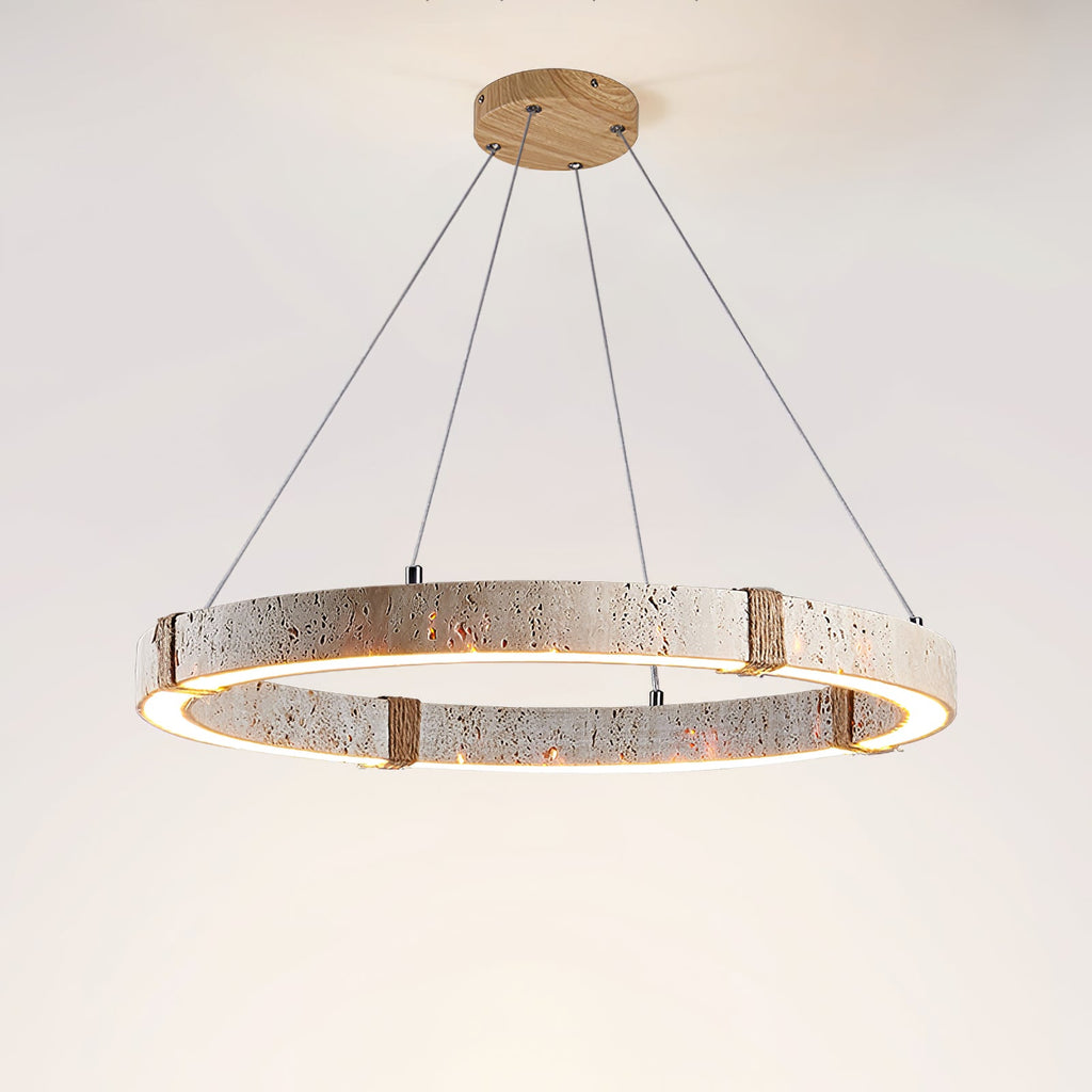 From below, the Clérachic travertine ring pendant glows warm along its inner edge, hung from a wooden ceiling plate on fine cables.