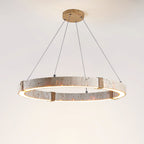 From below, the Clérachic travertine ring pendant glows warm along its inner edge, hung from a wooden ceiling plate on fine cables.
