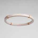 Tilted view of a Clérachic travertine ring pendant in pale pink-beige stone, with four rope-wrapped joints and a pale inner edge.