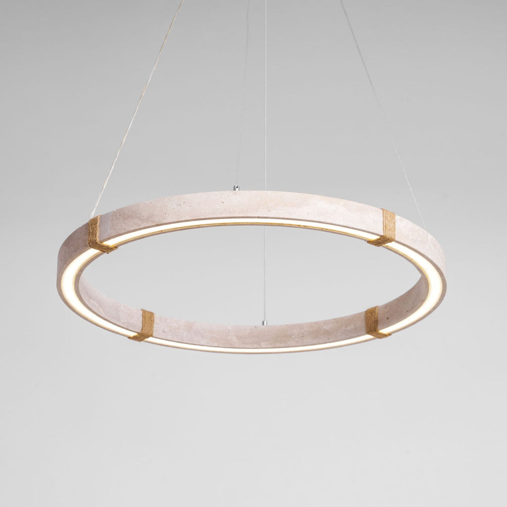 The pale travertine Clérachic ring pendant lit, with a warm glow along the inner edge and four rope-wrapped joints.