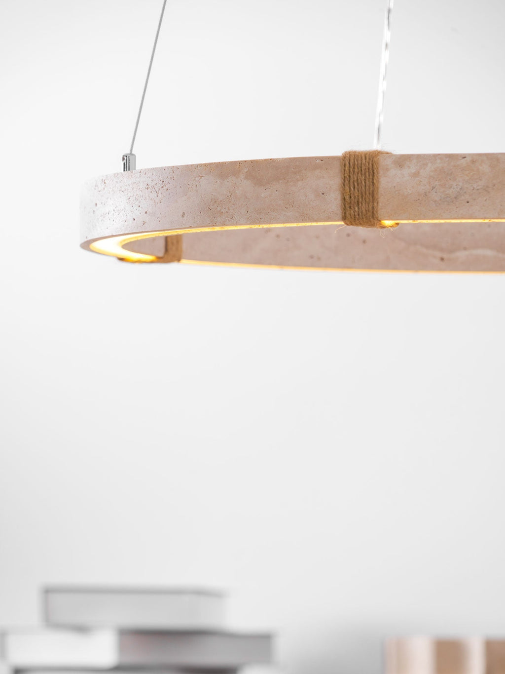 Close view of the stone edge and rope-wrapped joint of this Clérachic travertine pendant, with a warm light line on its underside.