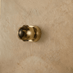 Clérachic round gold wall sconce with a polished domed shade and clear lenses, switched off, on a plaster wall