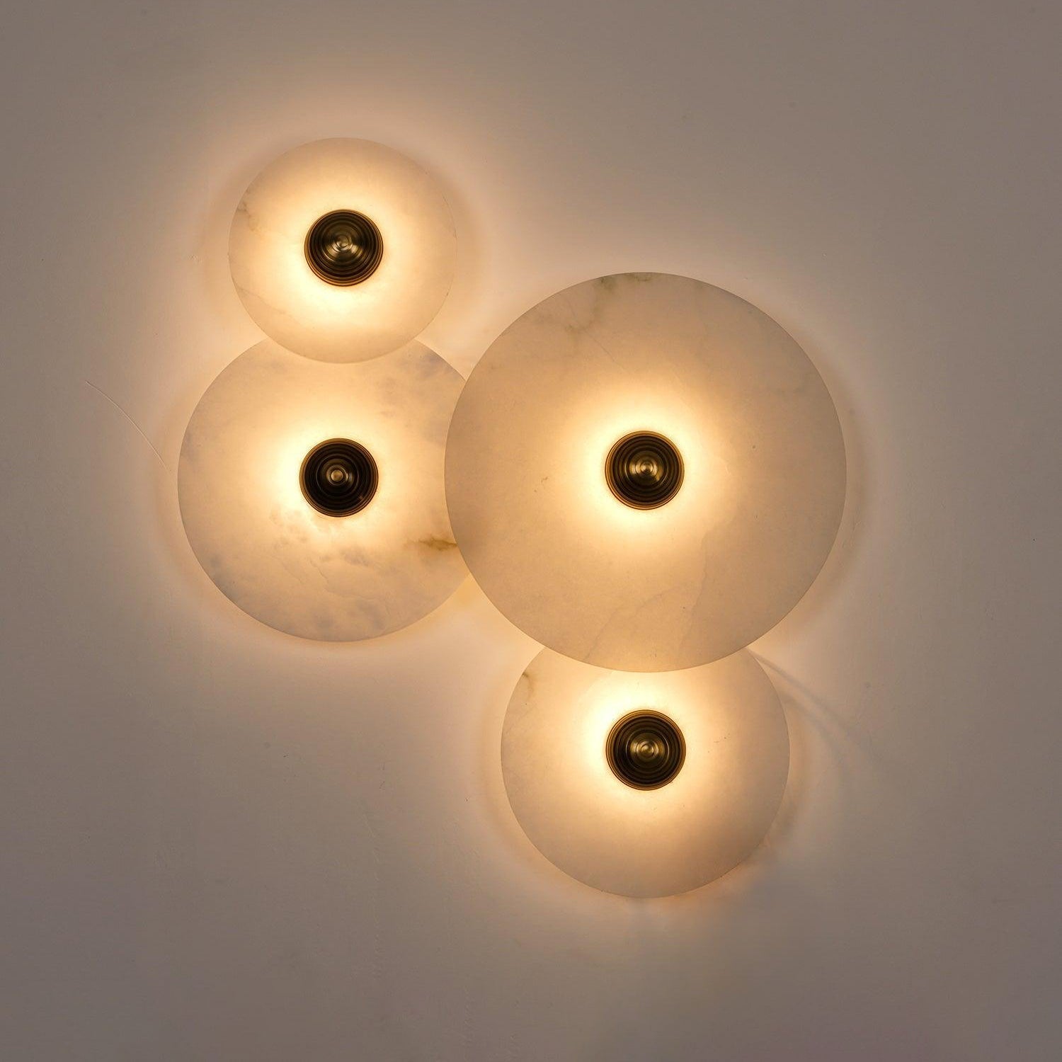 Four Clérachic round alabaster discs clustered and lit, brass bosses at each centre.