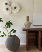 Three Clérachic round alabaster sconces grouped above a dark timber console table.