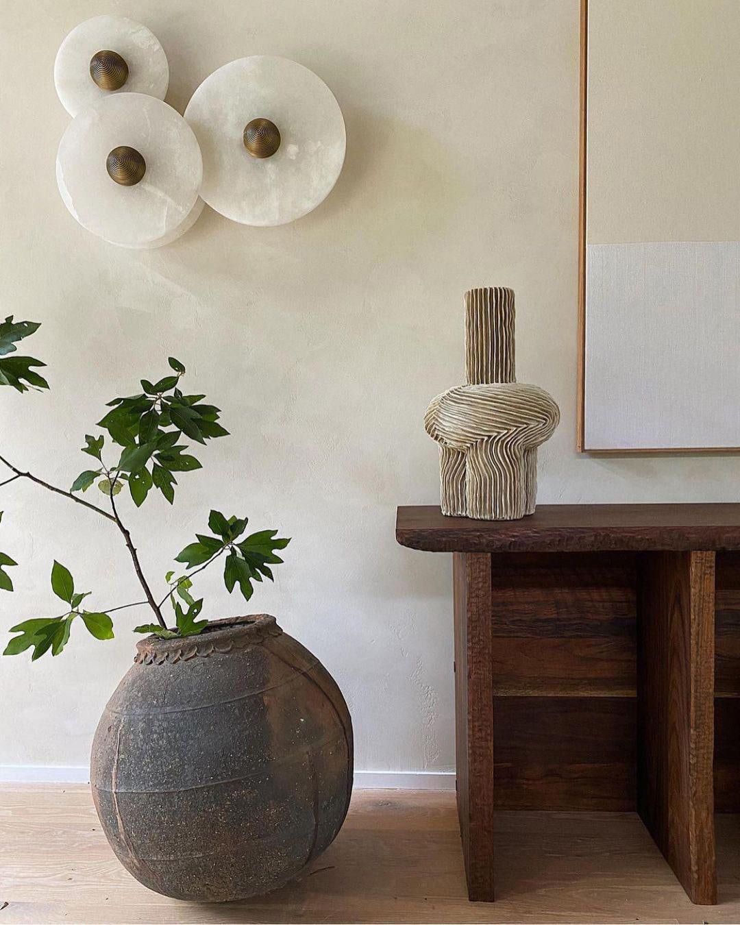 Three Clérachic round alabaster sconces grouped above a dark timber console table.