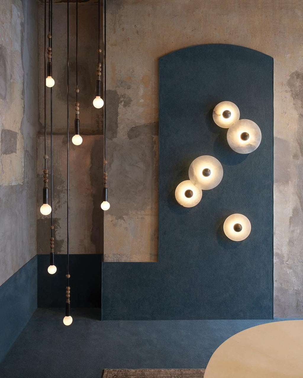 Clérachic round alabaster sconces scattered across a blue-painted alcove wall.