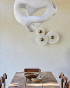 Three Clérachic round alabaster discs mounted beneath a sculptural plaster wall piece.