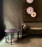Clérachic round alabaster sconces lit in a dim olive room above a low bench and table.