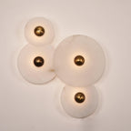 Four Clérachic round alabaster sconces lit close, veined stone glowing around brass centres.