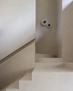Two Clérachic round alabaster sconces on a stair wall in soft daylight.