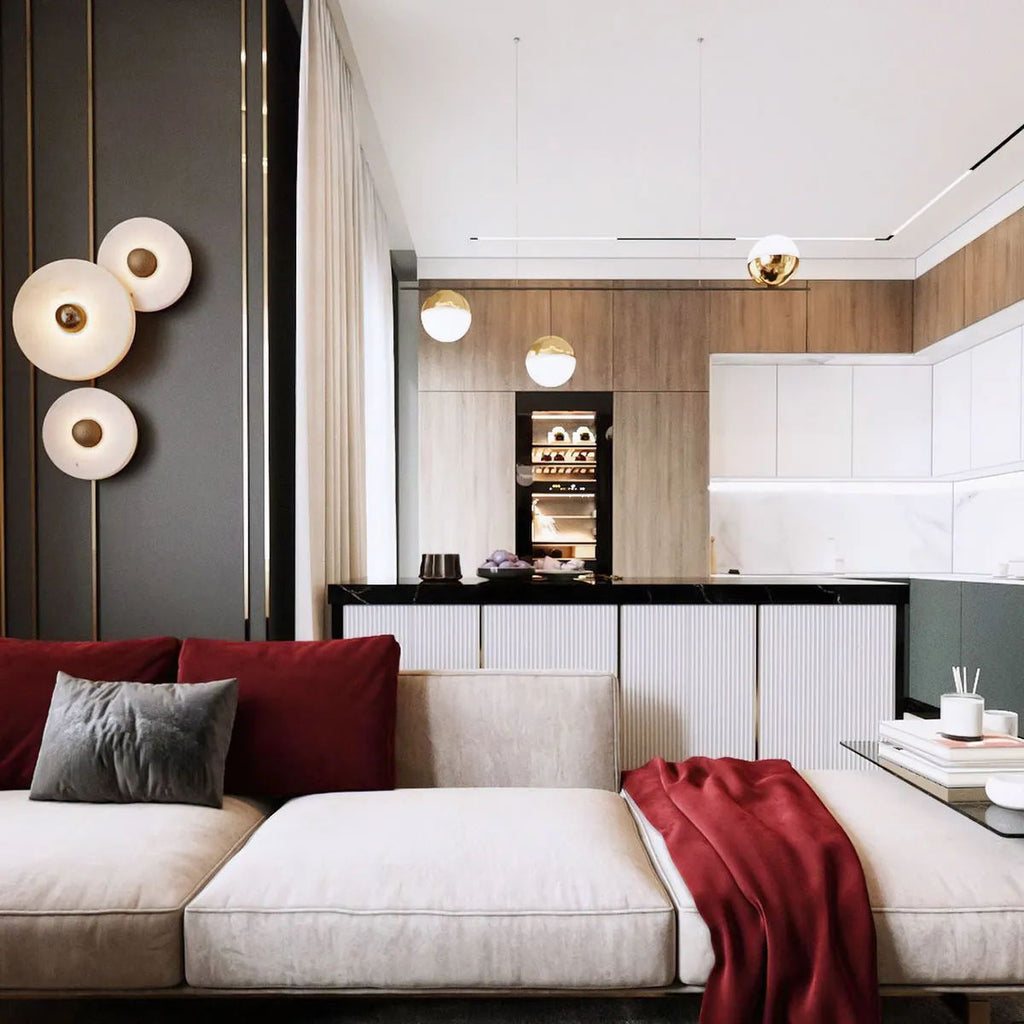Clérachic round alabaster sconces on a bronze panel beside a cream sofa and red throw.