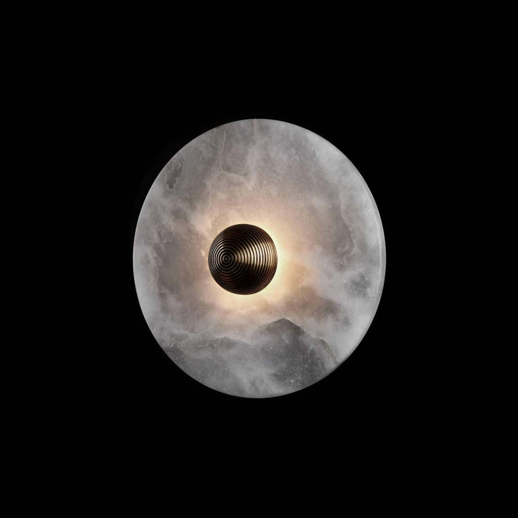 A single Clérachic round alabaster sconce on black, brass boss ringed by glowing stone.