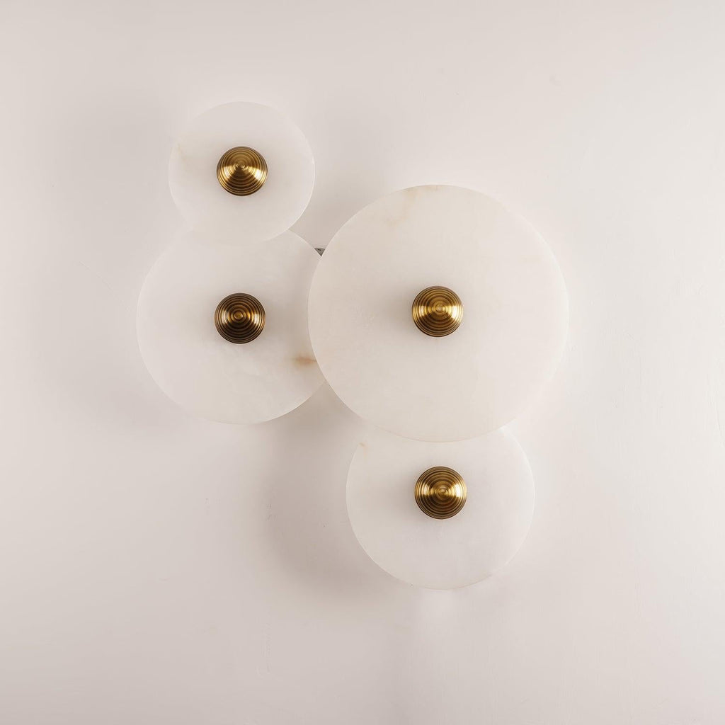 Four Clérachic round alabaster sconces unlit on white, brass fixings and stone grain in view.