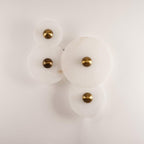 Four Clérachic round alabaster sconces unlit on white, brass fixings and stone grain in view.