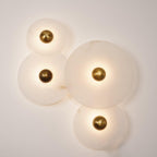 Four Clérachic round alabaster sconces lit warm, discs overlapping across the wall.