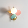 Multicolour Clérachic wall light on a pale grey wall, the lit glass globe framed by pink, mint-green and orange discs.