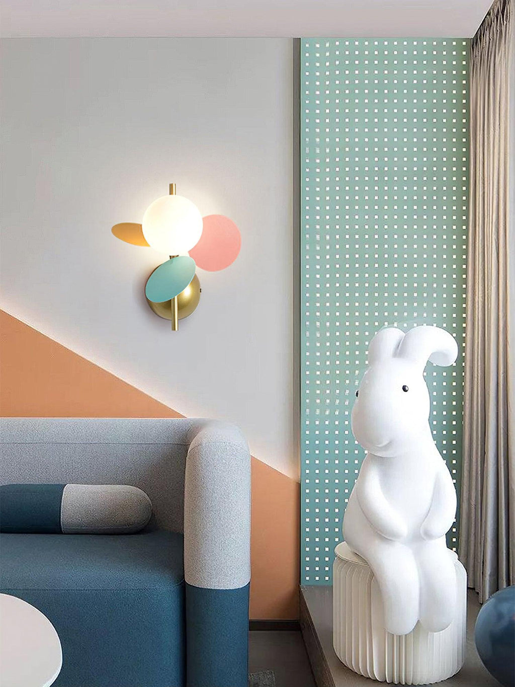 Multicolour Clérachic wall light in a play corner with a teal perforated panel, a blue sofa and a large white rabbit figure.