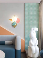 Multicolour Clérachic wall light in a play corner with a teal perforated panel, a blue sofa and a large white rabbit figure.