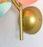 Close view of the brass dome backplate, screw and stem on this Clérachic wall light, with the mint and pink discs beyond.