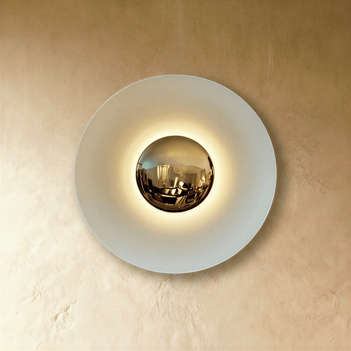 Clérachic round wall lamp in studio light: a pale white disc with a mirrored brass dome and a soft glow around it.