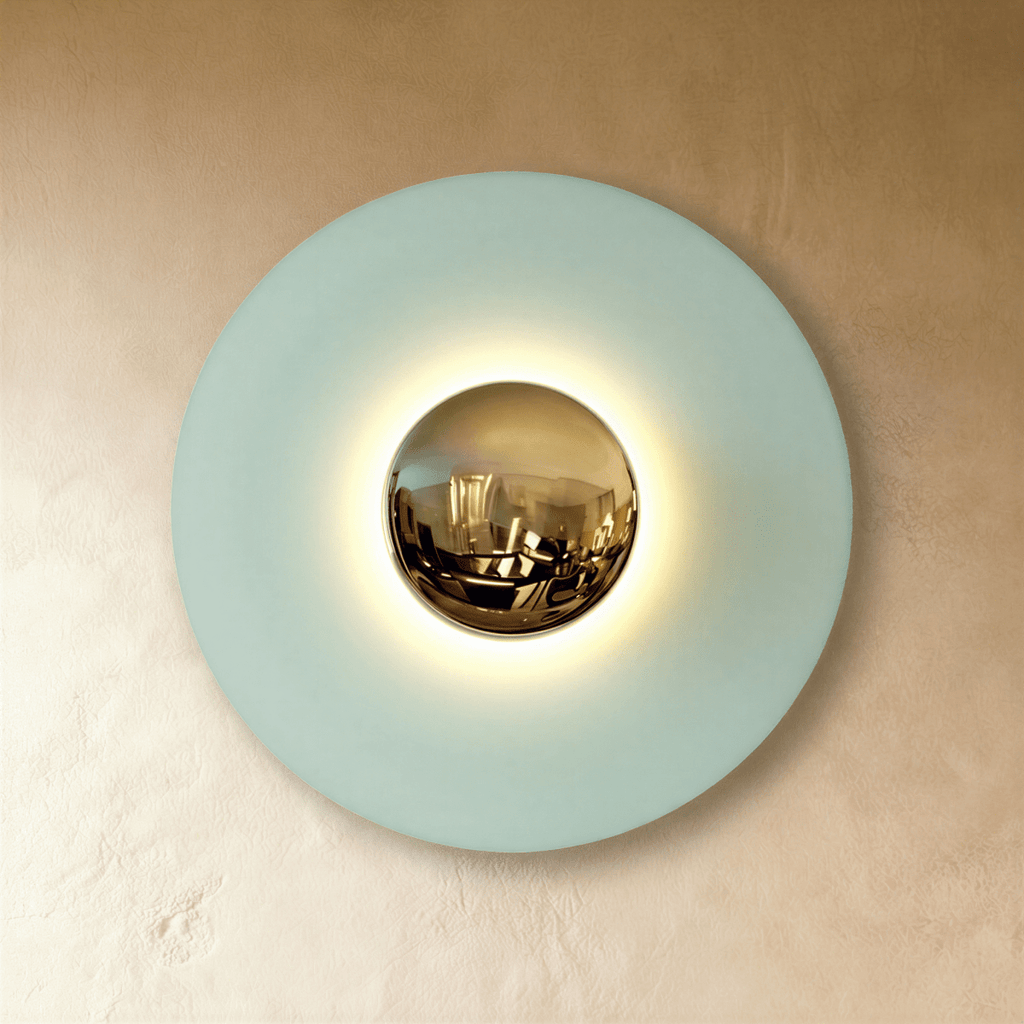 Clérachic larger round wall lamp in studio light with a pale blue disc, brass mirror dome and a soft warm halo.