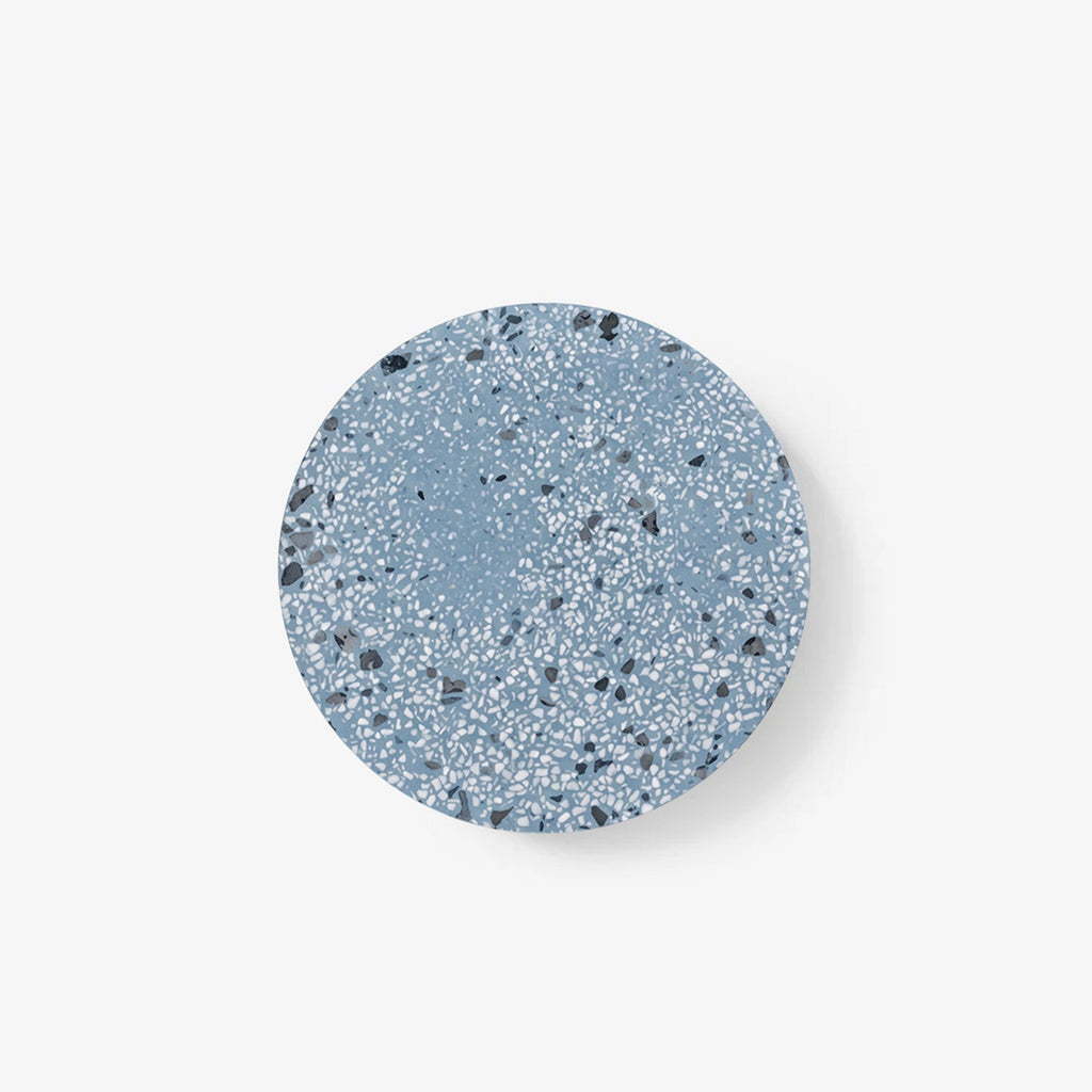 A Clérachic round wall light with a blue terrazzo face flecked in white and grey, on a plain white backdrop.