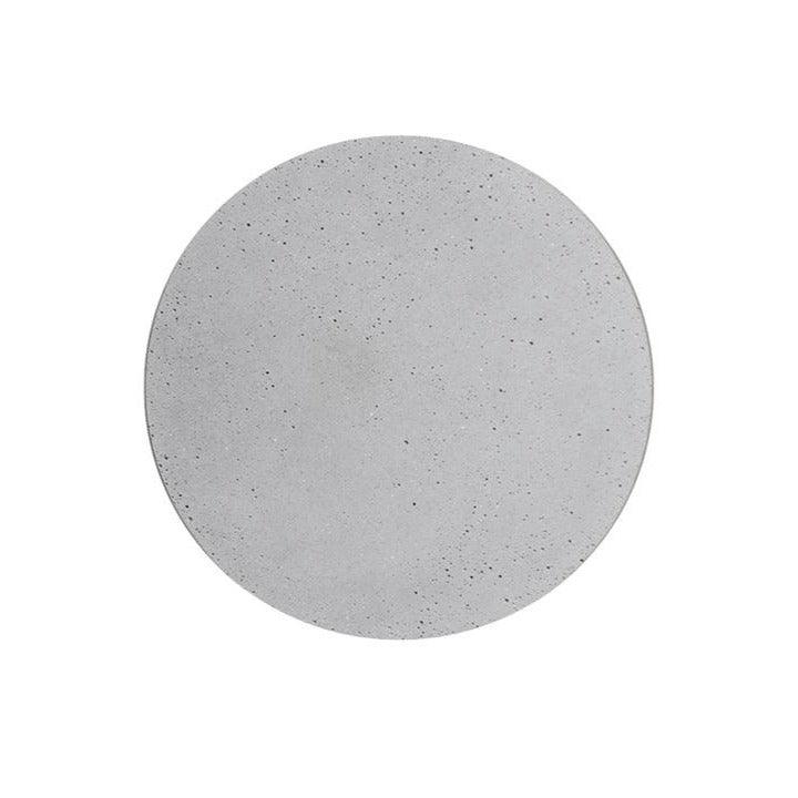 Front view of a Clérachic round wall light with a pale cement-grey face and fine pitted texture, on white.