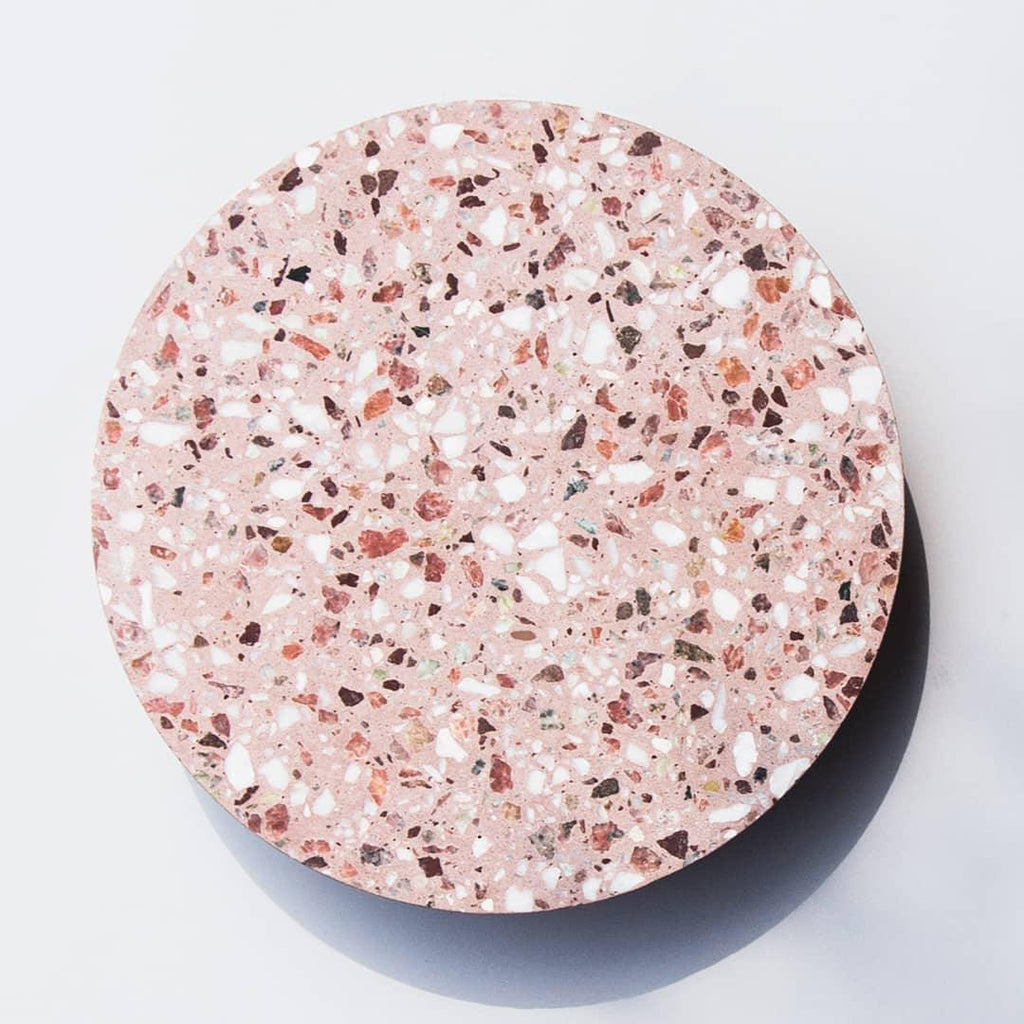 Close view of the pink terrazzo face of this Clérachic round wall light, set with white, red and dark chips.