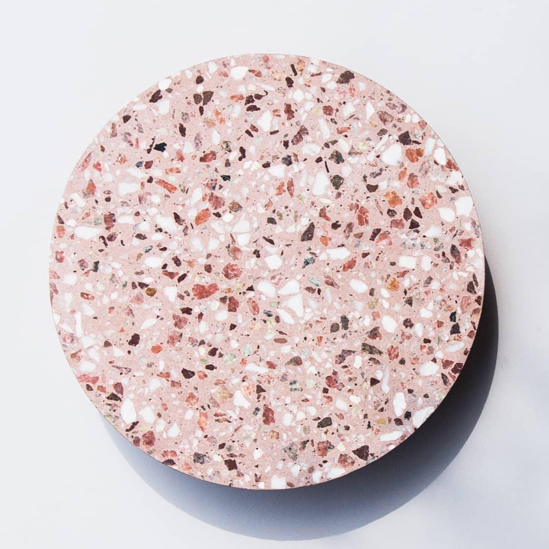 Close view of the pink terrazzo face of this Clérachic round wall light, set with white, red and dark chips.