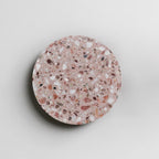 A Clérachic round wall light in pink terrazzo on a pale wall, with a soft shadow along its lower edge.