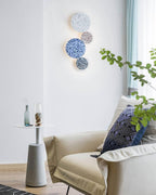 A stack of four terrazzo Clérachic round wall lights in white, pink, blue and black hangs above a cream sofa.