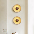 Two Clérachic travertine wall lights with walnut domes, stacked one above the other on a cream wall and lit warm.
