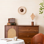 Unlit, a paler travertine version of this Clérachic wall light sits above a walnut cabinet with a rattan panel, a radio and a wooden sculpture.
