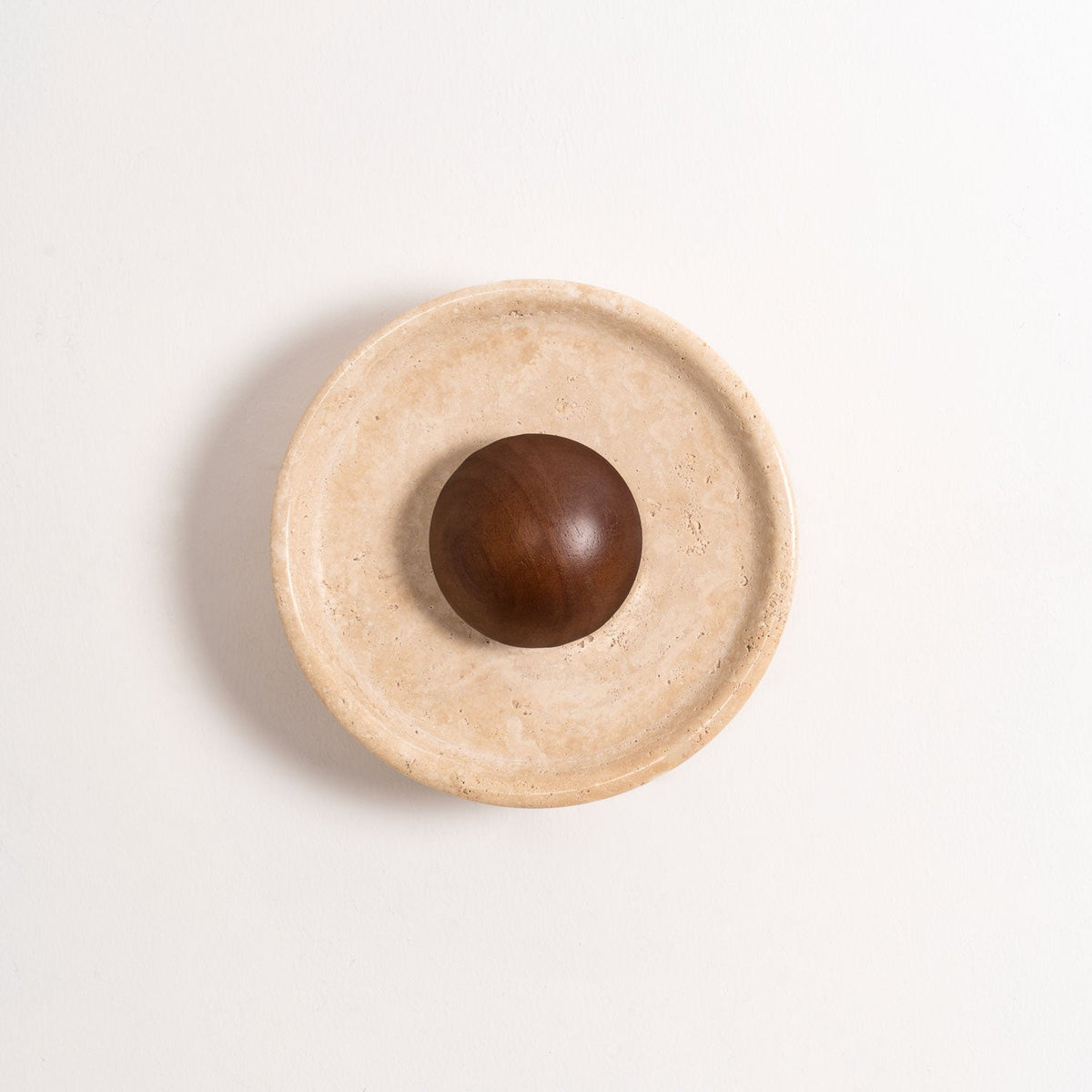 Unlit Clérachic travertine wall light with a walnut dome, shown straight on against a white wall with a soft shadow.