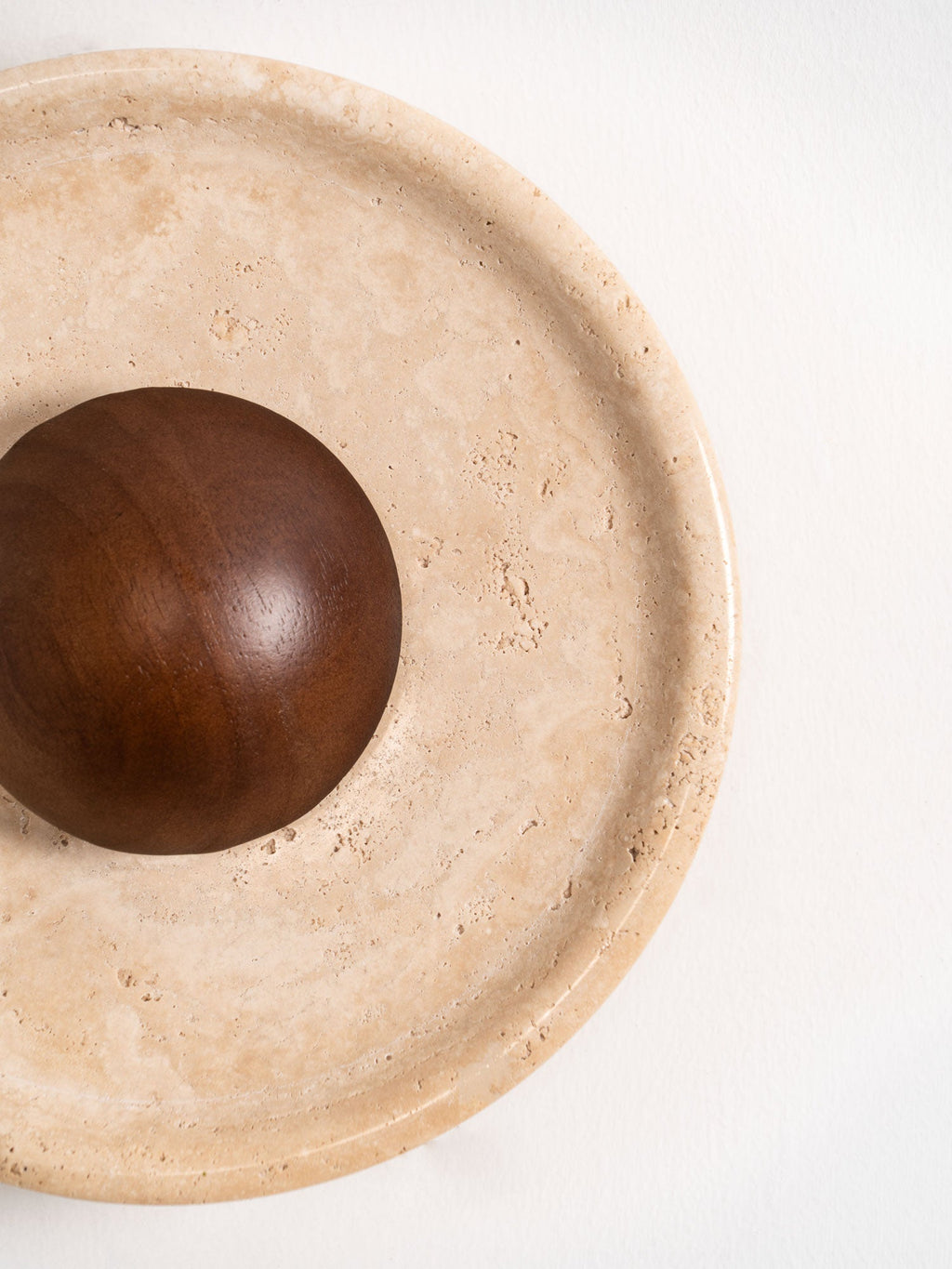 Cropped close view of the stepped stone rim and the polished walnut dome of this Clérachic travertine wall light.