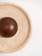 Cropped close view of the stepped stone rim and the polished walnut dome of this Clérachic travertine wall light.