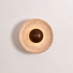 Unlit Clérachic travertine wall light with a walnut dome and a stepped rim, shown straight on against a pale wall.