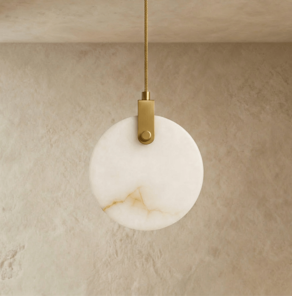 Clérachic round alabaster pendant switched off, showing its warm veining and a brushed brass-toned bracket on a braided cord.