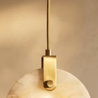 Clérachic close view of the brass-toned bracket, braided cord and cloudy alabaster disc of the pendant.