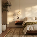 Clérachic alabaster pendant lit beside a low bed, with a floating walnut shelf, green throw and a floor plant nearby.