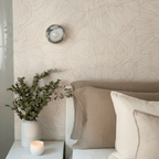 Clérachic wall lamp unlit above the same nightstand, its stone dome standing slightly proud of the leaf-patterned wallpaper.