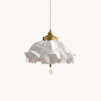 A Clérachic ruffled pendant light in white and pink on a plain off-white backdrop, with a brass cap, beaded trim and a crystal drop.