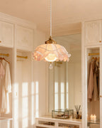 A Clérachic pendant glowing in a white dressing room with panelled wardrobes, hanging robes and a tall mirror behind it.